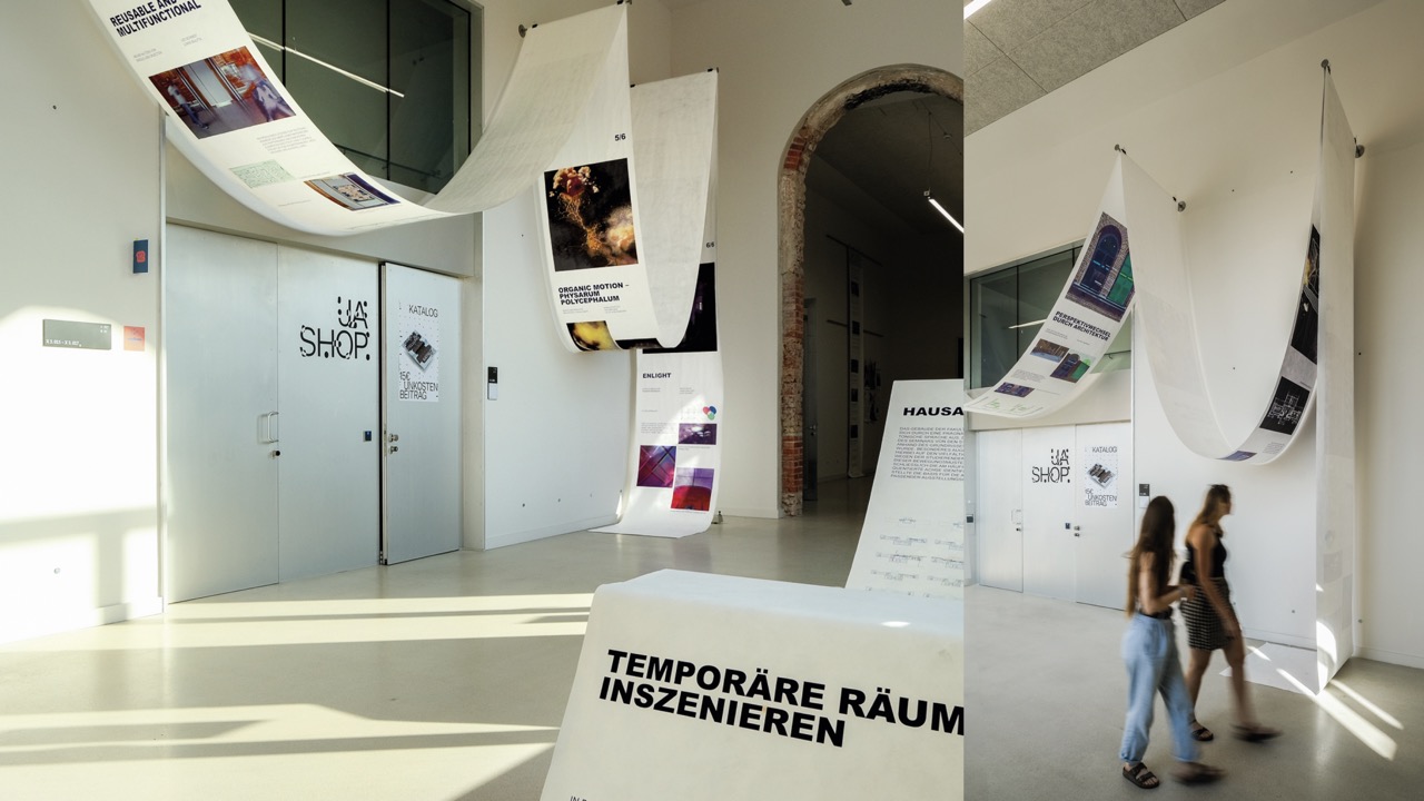 A high room with a 30m banner hung up in waves, on the left side and another banner on the right side, also draped in waves. The left banner has images on it, the right banner text, documenting a course called temporary room installation